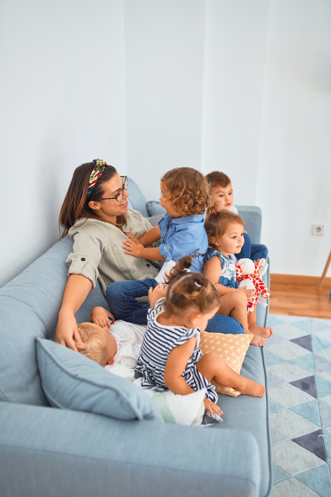 Betreuerin sitzt mit Kindern am Basteltisch