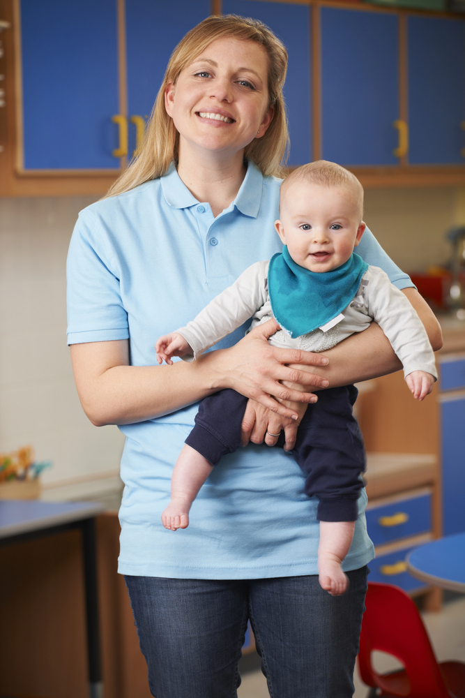 Junge Betreuerin spielt mit Kindern am Boden